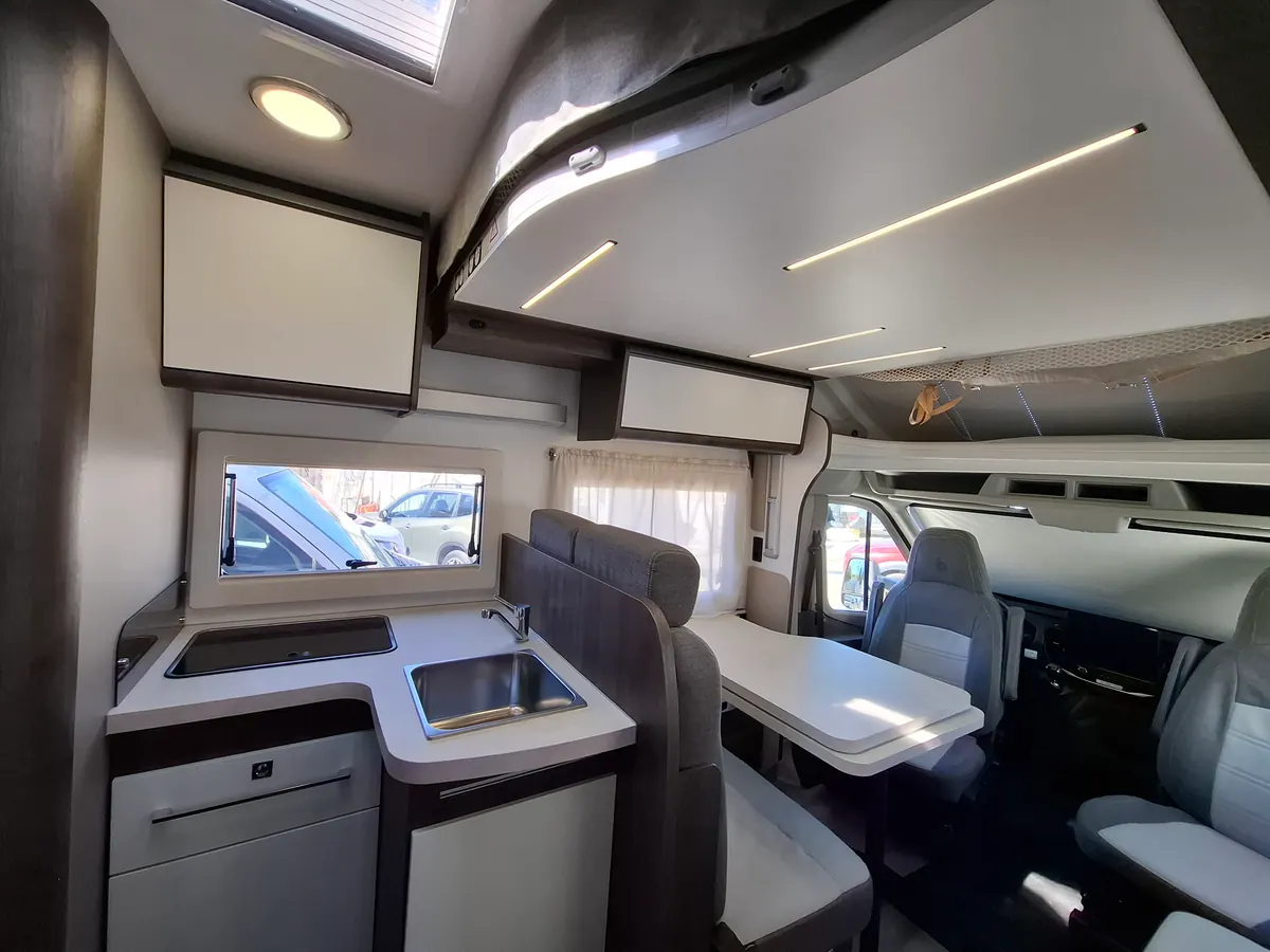 Cocina de la autocaravana perfilada con fregadero, encimera y armarios altos