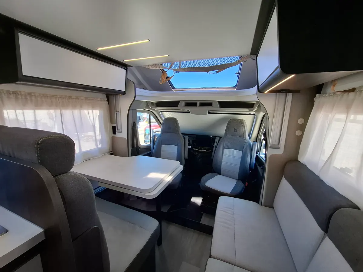 Salón comedor de la autocaravana perfilada con mesa y los asientos de la cabina girados